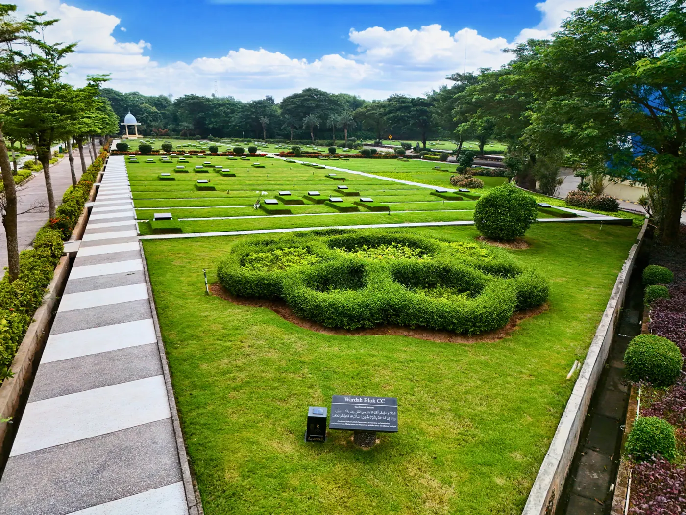 Taman bundar berpagar tanaman di tepi walkway