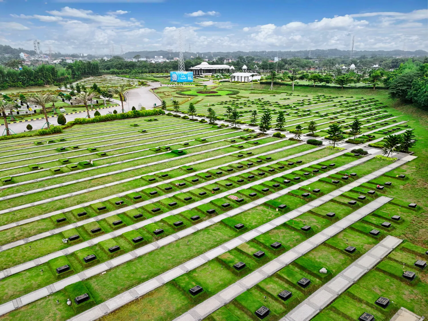 Deretan makam berumput dengan walkway beton di antaranya